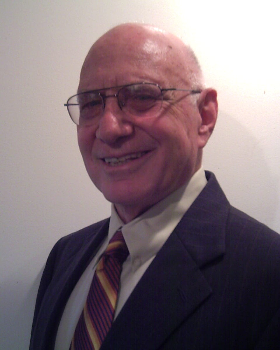 Herbert Robbins, PhD, Upper West Side psychologist, smiling in a navy suit and striped tie